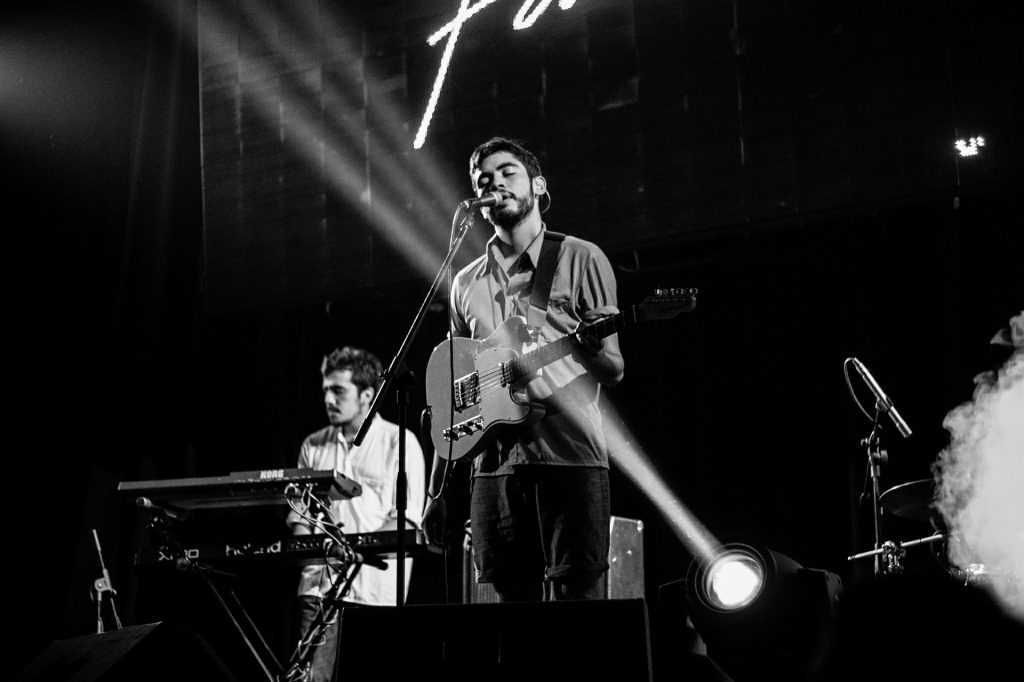  vocalista masculino de uma banda toca sua guitarra e canta.