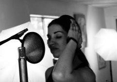 Female singer/vocalist stands with a microphone.